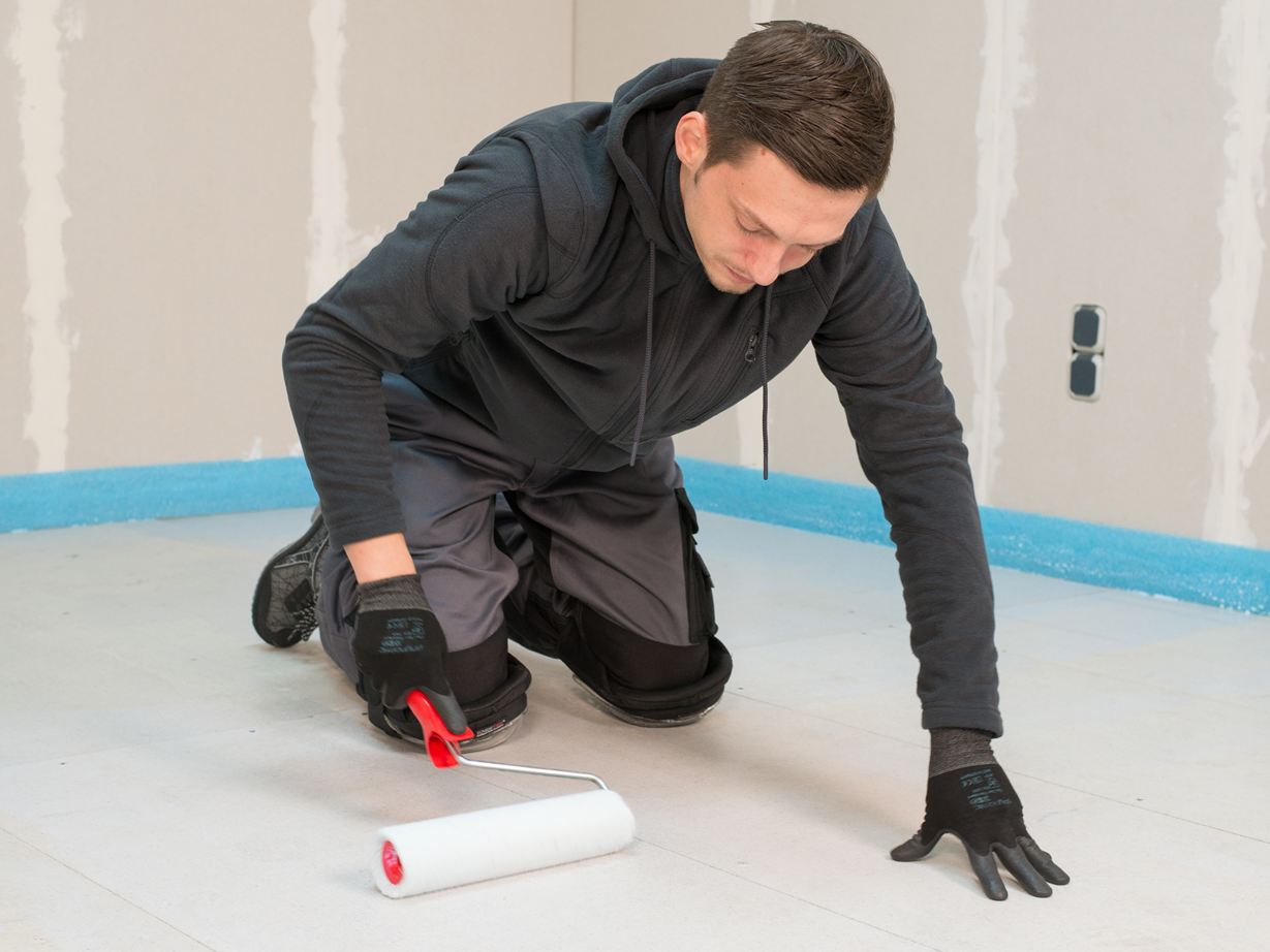 Obkladač nanáší základní nátěr válečkem