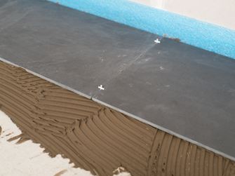 Spárovací kříže jako distanční prvky mezi dvěma břidlicovými dlaždicemi