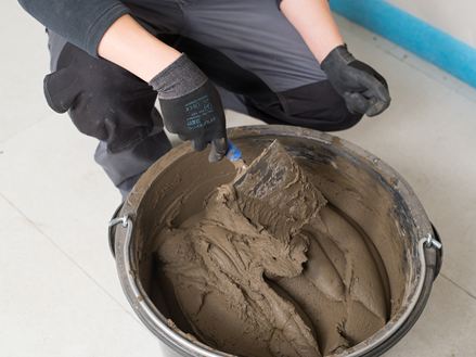 Obkladač míchá kbelík s maltou na přírodní kámen