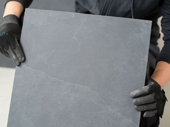 Obkladač drží břidlicovou dlaždici před kamerou