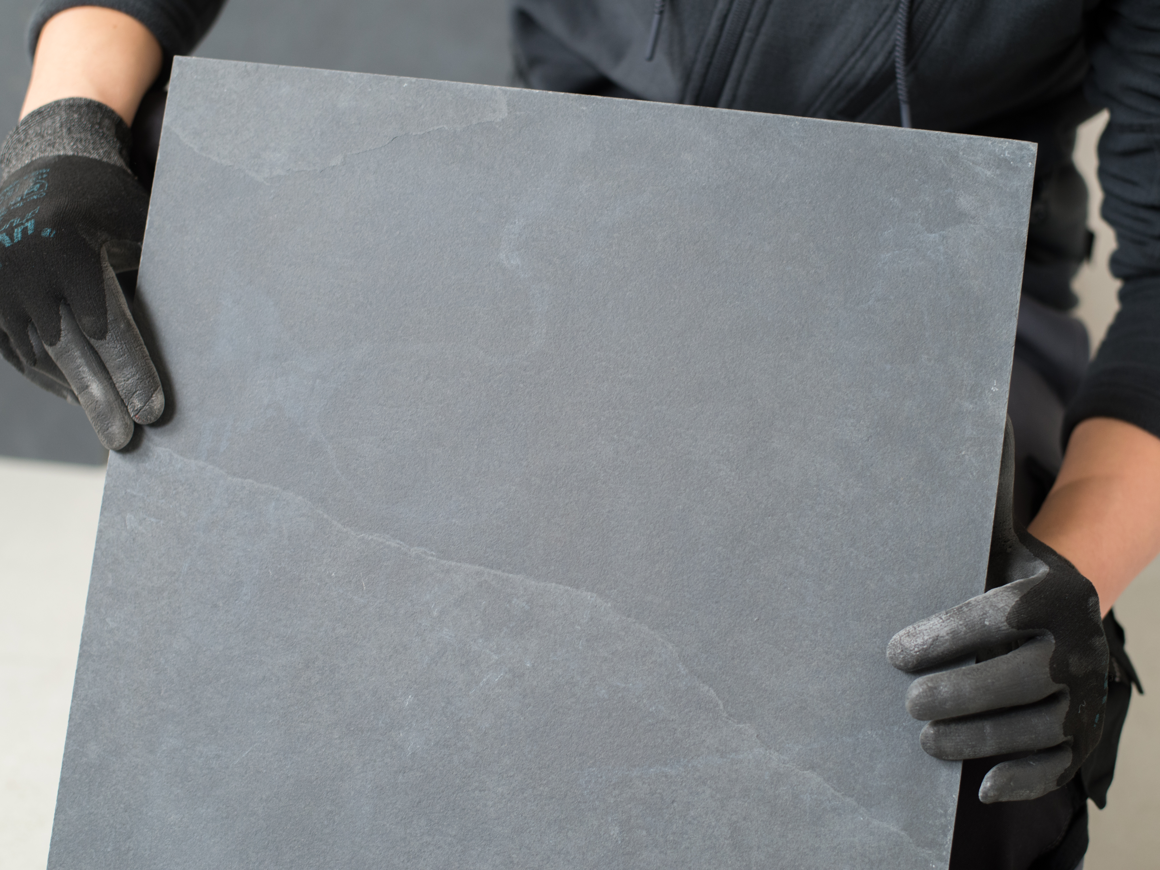 Obkladač drží břidlicovou dlaždici před kamerou