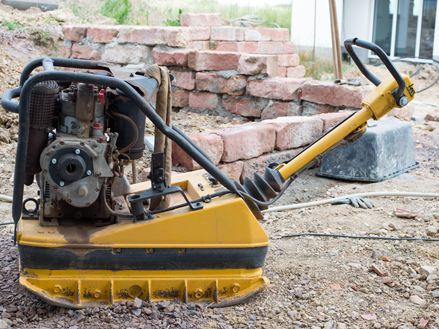 Fotografie vibrační desky na staveništi, která se používá ke zhutnění podkladové vrstvy.