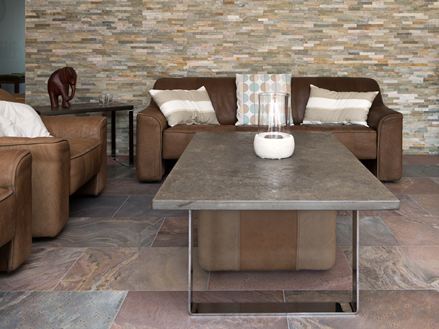 Obývací pokoj s hnědým sedacím nábytkem, načervenalou kvarcitovou dlažbou a obložením z přírodního kamene na stěně