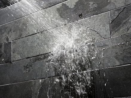 Voda na tmavé kamenné zdi v koupelně