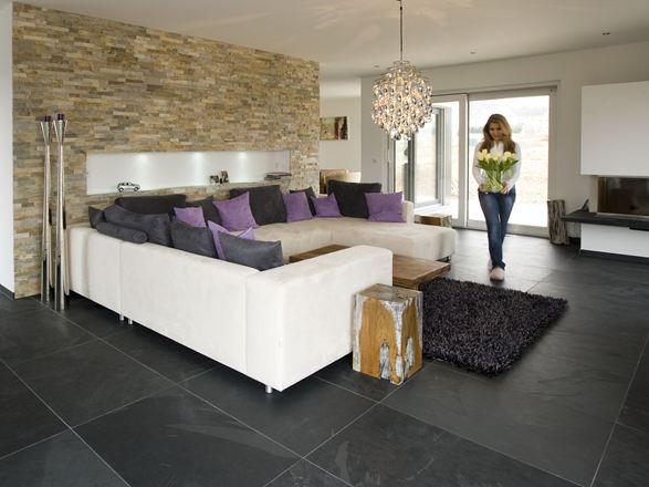 Moderní obývací pokoj s obložením z přírodního kamene na stěnách, břidlicovou dlažbou na podlaze a bílou pohovkou