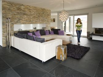 Moderní obývací pokoj s obložením z přírodního kamene na stěnách, břidlicovou dlažbou na podlaze a bílou pohovkou