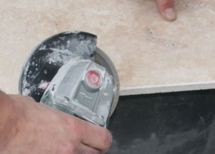 Kamenná deska je řezána úhlovým řezákem.