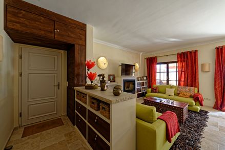 Obývací pokoj ve středomořském stylu se zelenou pohovkou a červenými závěsy